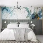 Sypialnia z tapicerowanym panelem ściennym i abstrakcyjną fototapetą