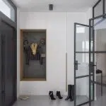 Wejście do mieszkania z dużą szafą w zabudowie i przeszklonymi drzwiami w czarnym kolorze