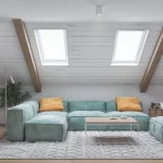 Pokój na poddaszu z dużą kanapą i skośnym sufitem z oknami